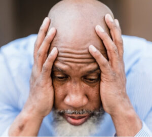 Man experiencing intense headache pain while holding his head.