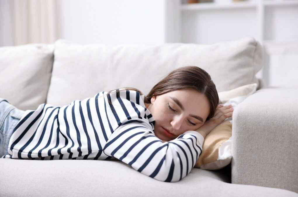 Woman resting on a sofa due to tiredness, which can be one of the common fibromyalgia symptoms.