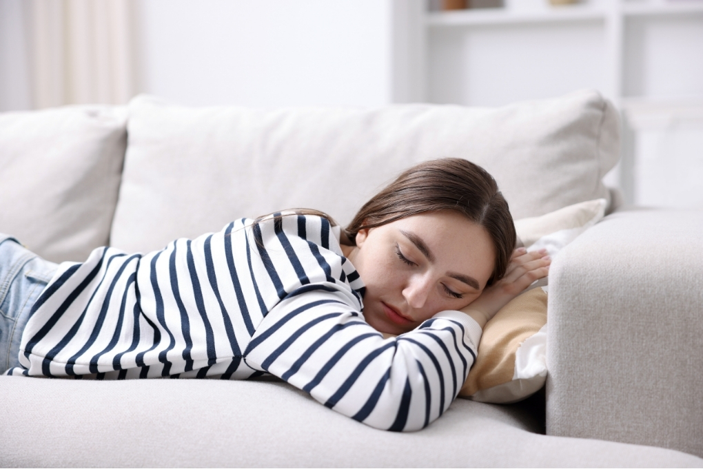 Woman resting on a sofa due to tiredness, which can be one of the common fibromyalgia symptoms.