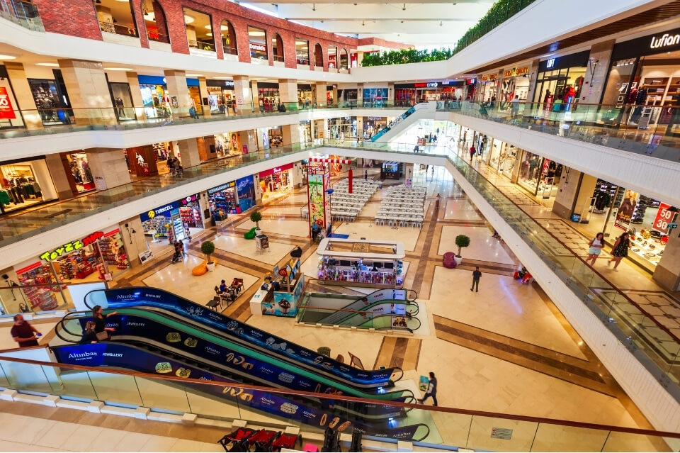Bright multi-level shopping centre with shops, escalators and visual activity, showing common environmental triggers for headaches in shopping centres.