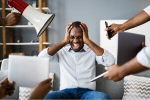 Man holding his head while surrounded by loud noise and competing demands, representing sensory overload linked to headaches in shopping centres.