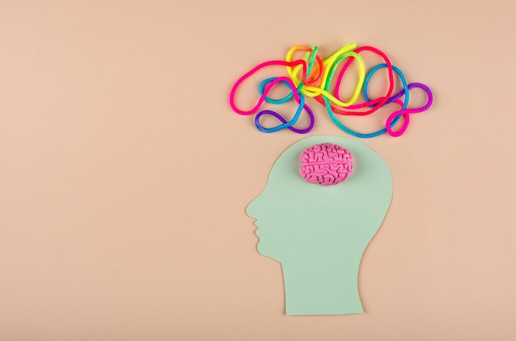 Paper head with a small brain and tangled colourful cords above it, symbolising disrupted brain and body communication in functional neurological disorder.