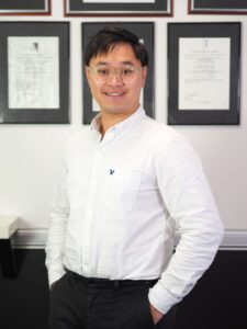 Austin Chua standing in front of certificates on the wall in a portrait photo.