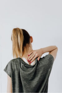 Woman holding neck, indicating symptoms linked to vestibular migraine