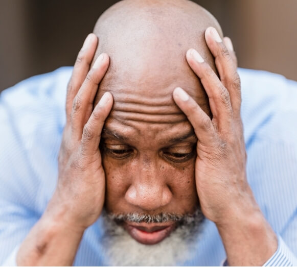Man experiencing intense headache pain while holding his head.