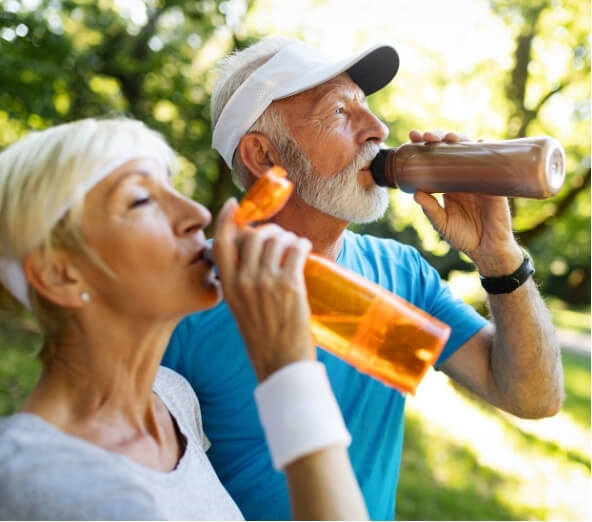 Older man and woman hydrating outdoors after exercise, highlighting the importance of water intake to prevent exercise-induced migraines.