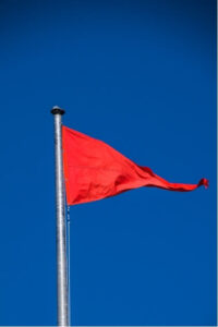 Bright red flag waving against a blue sky, symbolising urgent headache red flags that should not be ignored.
