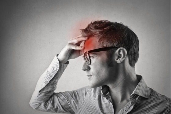 Black and white photo of a man holding his forehead in pain, with a red highlight showing headache location—indicating a potential red flag symptom.