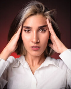 Woman experiencing a medication overuse headache, holding her temples.