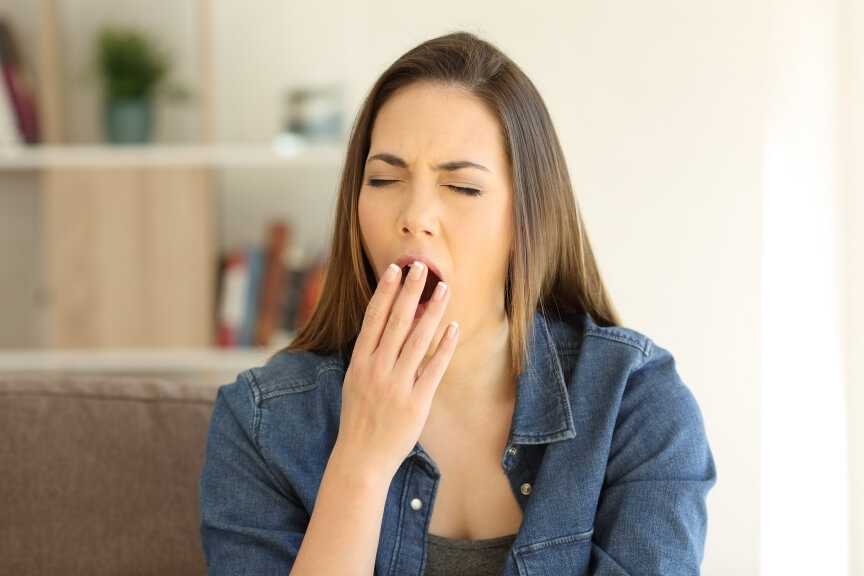 Woman yawning and feeling fatigued, a common early sign of migraine prodrome symptoms